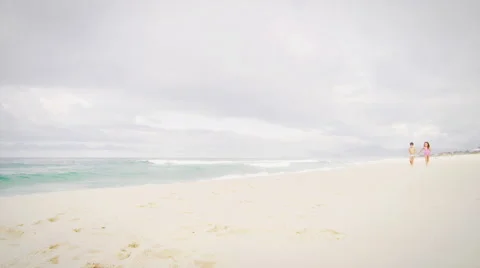Siblings walk down a beach holding hands Video stock 49548570