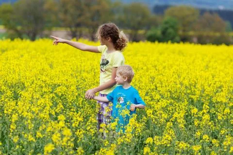 Siblings walking through yellow rape field Stock Photos