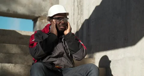 Sick african american worker sits on construction site and massages his head Stock Footage 193107476