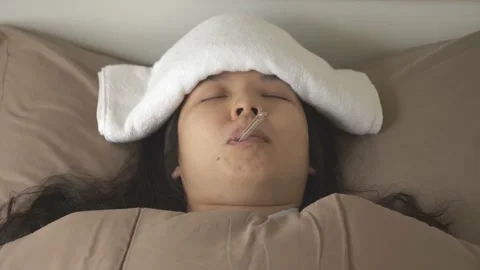 Sick Asian woman lying on bed, measuring body temperature with oral thermometer Stock Footage 146001553
