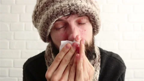 Sick bearded man in knitted hat blowing his nose feeling cold  close up Stock Footage 150110071