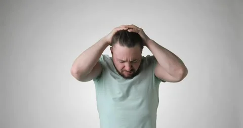 Sick bearded young man in green t-shirt putting hands on head having headache. Stock Footage 149030855