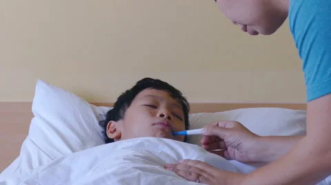 Sick boy lying in bed and mother checking his temperature Stock Footage 63580036