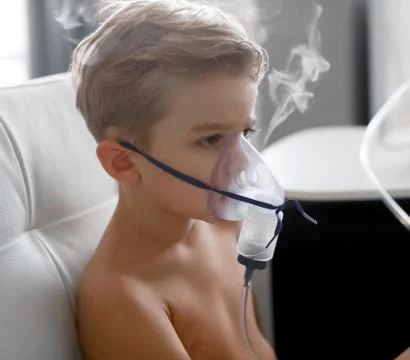 Sick boy in nebulizer mask making inhalation, respiratory procedure by pneumonia Stock Photos