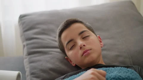 Sick Boy Resting on Couch, Covered with Blue Blanket, Coughing and Adjusting Stock Footage 305702625