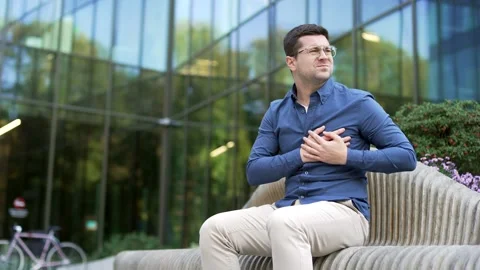 Sick businessman has heart attack, suffering from chest tension sitting on bench Stock Footage 307490486