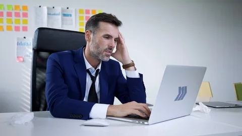 Sick businessman with headache trying to work on laptop in office Stock Footage 114814097
