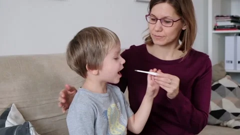 Sick child boy being checked for fever and illness, mother taking care of her Stock Footage 102107798