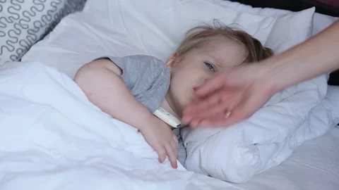 Sick child boy laying in bed and mom hand taking temperature.  Stock Footage 93865713