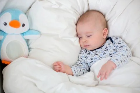 Sick child boy lying in bed with a fever, resting at home Stock Photos