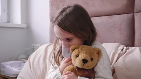 Sick child inhaling using nebulizer with her teddy bear Stock Footage 303341573