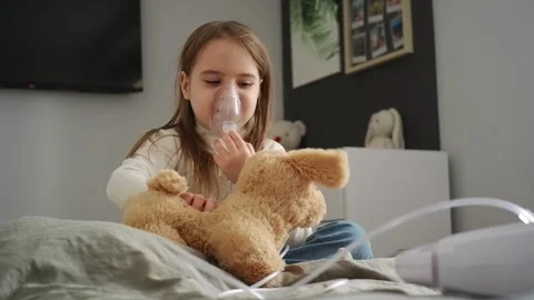 Sick child playing with teddy bear while inhaling medicine Video stock 303483833