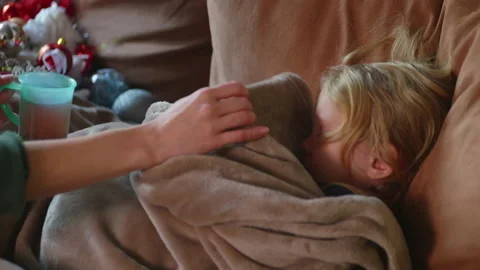 Sick child refuses to have warm drink while lying on the sofa with fever Stock Footage 230647417
