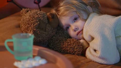 Sick child resting on the sofa watching TV, struggling of fever, cute bear near Stock Footage 233066827