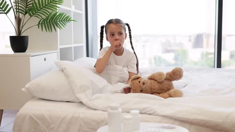 Sick child sitting on bed and covering mouth while coughing Stock Footage 252642667