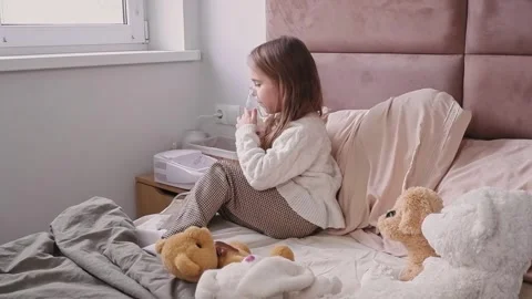 Sick child using inhaler on bed with teddy bears Stock Footage 303341773