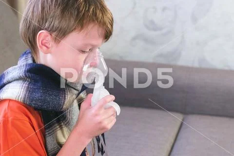 Sick cute boy inhaling through inhaler mask. Use nebulizer and inhaler for the Stock Photos