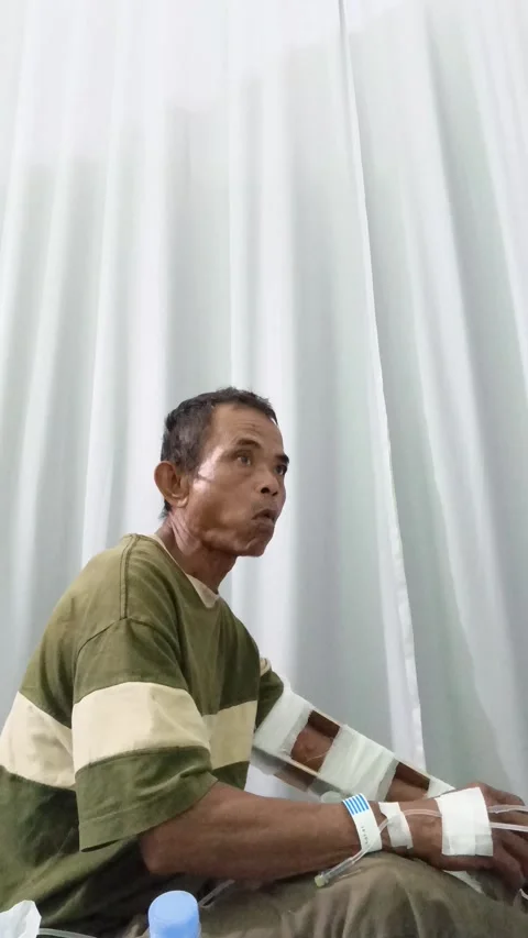 Sick elderly Asian patient eating alone on a hospital bed with an IV drip 스톡 동영상 335019666