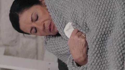 Sick elderly in blanket sitting on sofa at home, sneezing. Stock Footage 146451373