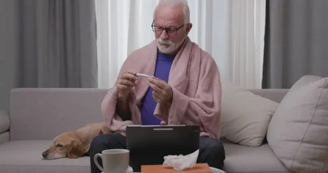 Sick elderly man checking his temperature suffering from seasonal flu or cold 스톡 동영상 166468817