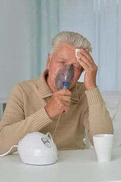 Sick elderly man makes inhalation at home Stock Photos