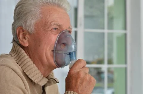 Sick elderly man makes inhalation at home Stock Photos