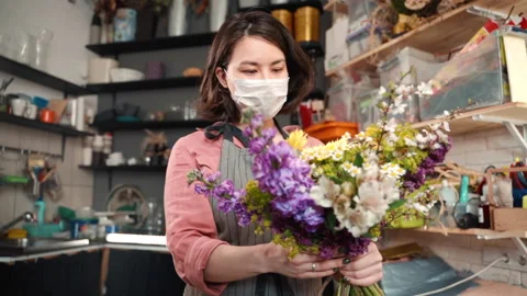 Sick female in preventive mask checking estimating bouquet arrangement. florist Stock-Footage 132301186