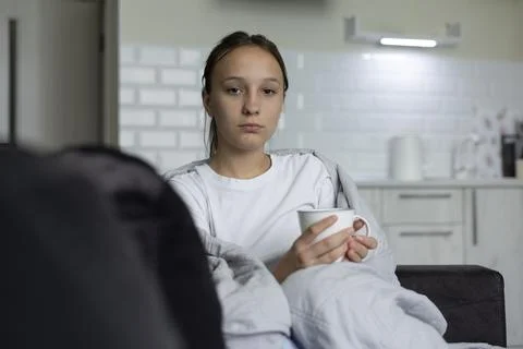 Sick girl with cold symptoms using tissue at home 库存照片
