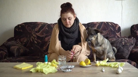 Sick girl sitting on couch throws a effervescent tablet in a glass of water Stock Footage 116562994
