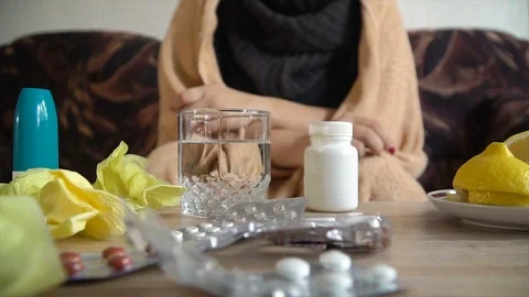 Sick girl sitting on couch throws a effervescent tablet in a glass of water Stock Footage 116623770