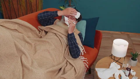 Sick ill senior man suffering from cold or allergy lying on home sofa sneezes Stock Footage 219345405