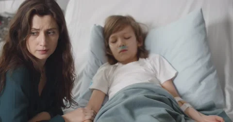 Sick kid boy with lying in bed at hospital and mother holding his hand Stock Footage 149318034