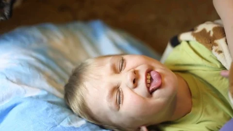 Sick little boy, lying in bed with a flu and a fever, watching TV Video stock 74490016