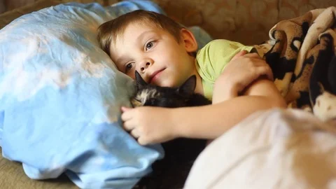 Sick little boy, lying in bed with a flu and a fever, watching TV Video stock 74490097