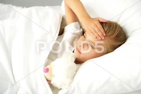 Sick little girl in bed Stock Photos