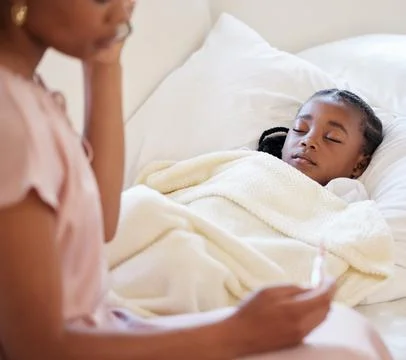 Sick little girl in bed while her mother uses a thermometer to check her Stock Photos
