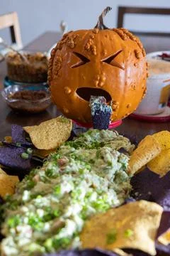 A sick looking pumpkin throwing up green stuff on a plate of chips Stock Photos