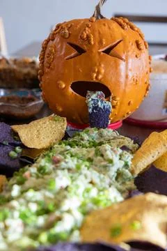 A sick looking pumpkin throwing up green stuff on a plate of chips Stock Photos