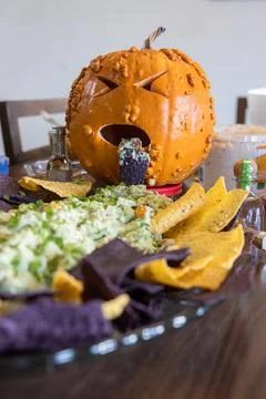 A sick looking pumpkin throwing up green stuff on a plate of chips Stock Photos