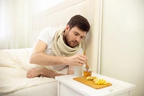 Sick Man in Bed Adding Honey into Tee. Man Ill in Bed Self Healing. Self Stock Photos