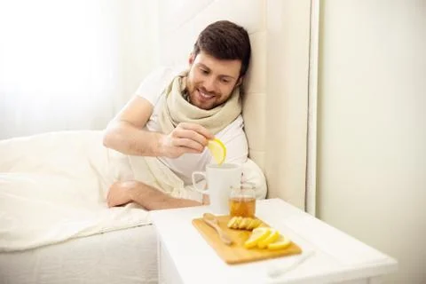 Sick Man in Bed Adding Lemon into Tee Smilling. Man Ill in Bed Self Healing Stock Photos