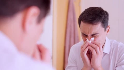 Sick man blowing nose while looking in mirror Stock Footage 311305906