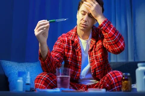 Sick man checking fever with a thermometer. Home treatment of illness, seas.. Stock-Fotos