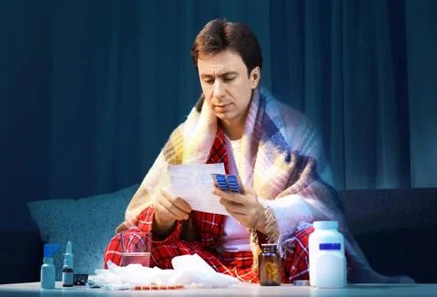 Sick man with cold and flu symptoms reading a prescription for medicine and.. Fotos de archivo