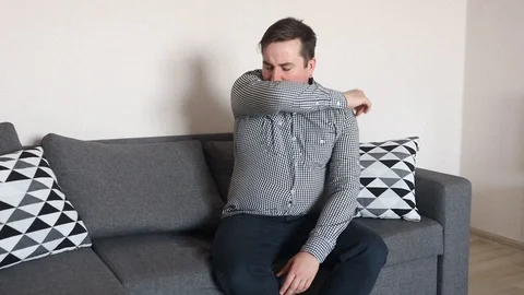 Sick man with a cold or flu coughing in his sleeve or elbow Stock Footage 126711261