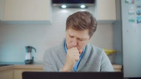 Sick man coughs at home while sitting at laptop Stock Footage 148343293