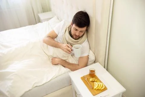 Sick Man Drinking Hot Tea in Bed at Home. Ill Man at Home Self Treatment. Stock Photos