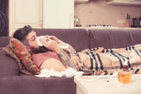 Sick man feeling cold, lying in the bed and blowing his nose. Stock-Fotos