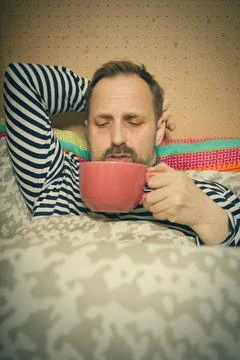 Sick man with flu and cold healing fever and sickness with cup of hot tea Stock Photos