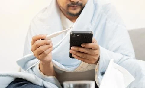 Sick man with flu holding a termometer and check  temperature with medical .. Stock Photos
